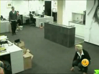 Gif animado de un hombre saltado a un puf de bolas en la oficina y explota