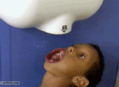 Niño gracioso debajo del secamanos de un lavabo se mueve la boca