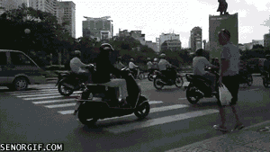 gif-hombre-cruzando-carretera-entre-cientos-motos-coches-que-no-se-paran.gif